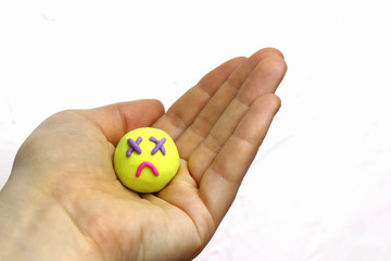 Sad face from multi-colored plasticine on a white background. Copy space - the concept of a bad mood, sadness, expression of emotions, disappointment, illness.