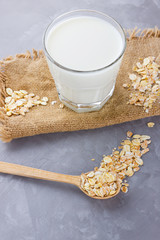 Oat milk. Organic oat milk on sackcloth. Healthy vegan non-dairy organic drink with oat flakes. Healthy alternative milk on cement background. Zero waste. Copy space