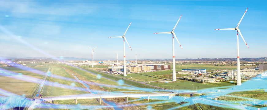 Centrale eolica in pianura con turbine e industrie come sfondo. Fonte di energia elettrica ecologica verde rinnovabile. Panoramica.