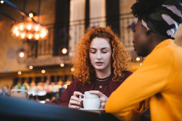 A young woman is talking with a female friend about her problem in a cafe.