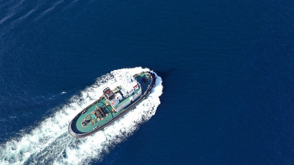 Aerial drone photo of tug assisting boat cruising near commercial container area of Perama, Attica,...