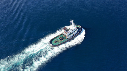 Aerial drone photo of tug assisting boat cruising near commercial container area of Perama, Attica, Greece