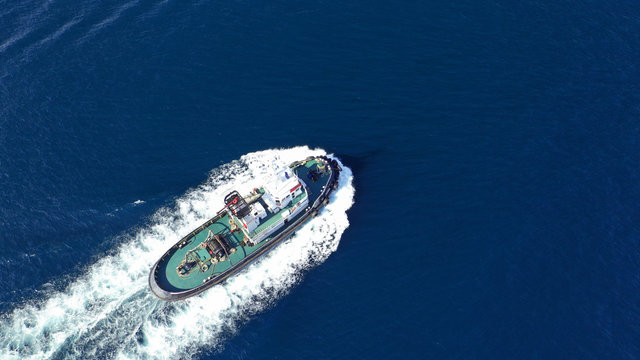 Aerial drone photo of tug assisting boat cruising near commercial container area of Perama, Attica, Greece