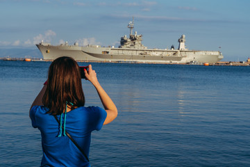 Warship. A girl takes a warship on her cell phone.