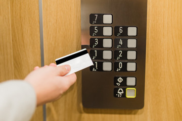 Close up of man holding cardkey on control panel elevator access concept.
