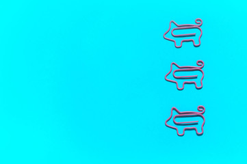 top view of vertical line with pink piggy paper clips on turquoise background, business strategy concept