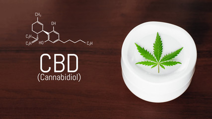 Bank of medical cream with CBD oil, hemp leaf. Jar with hemp lotion on dark background with the formula CBD cannabidiol