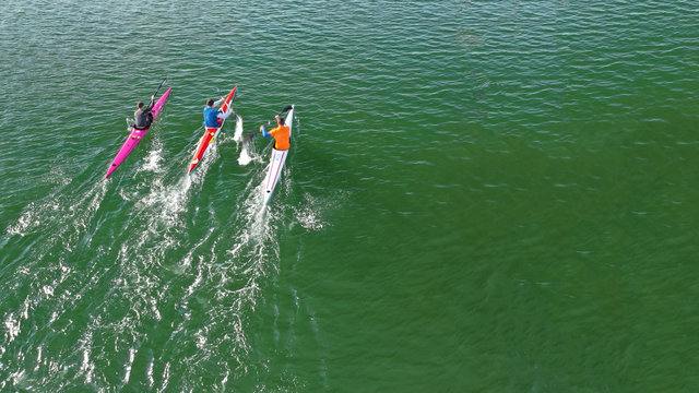 Aerial drone photo of athletes competing in canoe race in tropical lake with emerald waters