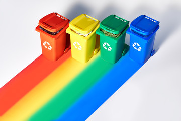 Four color coded recycle bins, isometric projection on geometric rainbow paper background with...