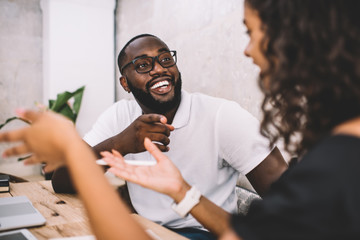 Cheerful black guy pointing at coworker