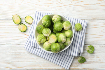 Bowl with brussels sprout on wooden background, top view