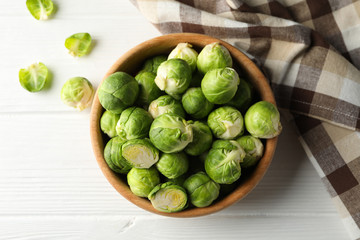 Bowl with brussels sprout on wooden background, top view
