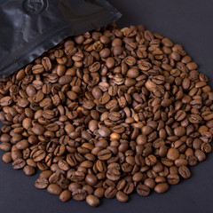 Coffee beans spill out of a black pack. Coffee background.
