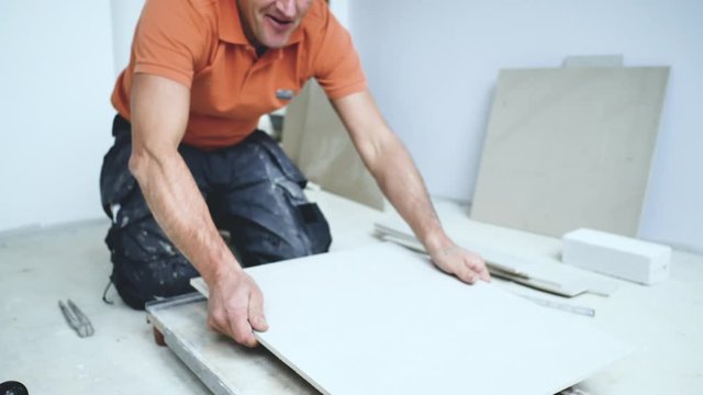 Handwerker schneidet grosse fliesen mit Fliesenschneider in einem neubau haus 4k Video in zeitlupe