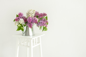 Bouquet of lilac in tin jug on white background. With space for your text