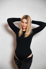 Fototapeta premium Beautiful glamour long hair woman posing for camera photographer wearing plack body with jeans - Portrait at a grey seamless background studio wall