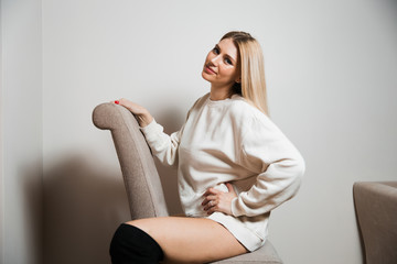 Beautiful glamour long hair woman posing for camera photographer wearing white sweater on naked body - Portrait at a grey seamless background studio wall