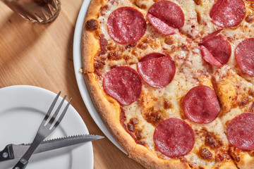 Close up on wooden table with salami pizza.
