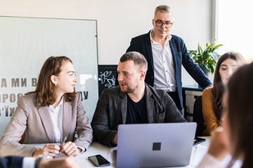 Group of happy diverse male and female business people in formal gathered around laptop computer in office