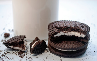 Delicious sandwich cookies with a glass of milk. Gluten-free cornmeal cookies, black.  healthy eating concept, flat lay White background