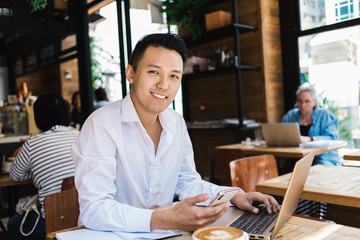 Fototapeta na wymiar Smiling freelancer using gadgets in coffee shop
