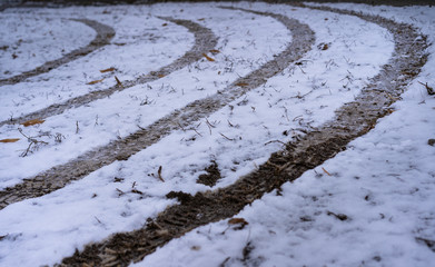 Fototapeta na wymiar Traces of a car on the ground with snow