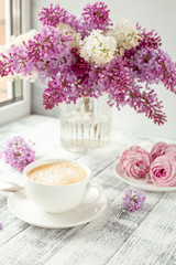 Cup of coffee, homemade marshmallow, lilac flowers. Romantic spring morning Selective focus