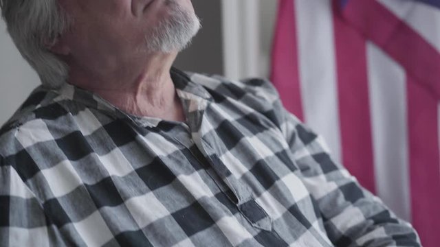 Camera moving up from US Army stripe to face of grey-haired Caucasian man with brown eyes. Old veteran sitting in wheelchair and recalling memories. Lifestyle, disability, patriotism, discharge.