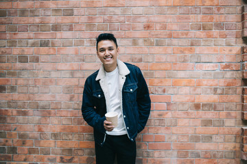 Positive guy in front of urban brick wall
