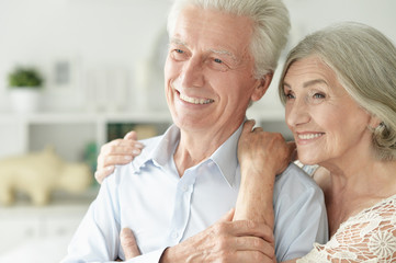 Portrait of cheerful senior couple embracing at home