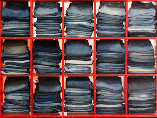 Folded Jeans Kept On Red Shelves In Second hand Shop.