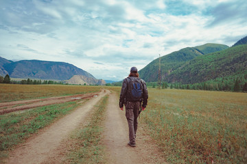 Naklejka premium guy with a backpack near the mountains