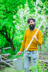 Spring. Work in garden. Smiling man preparing to planting. Plants. Watering. Gardening. Bearded gardener with garden watering can and spade. Gardener work. Farm. Farmer working in garden.