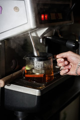 bartender pours boiling water from coffee machine into author's tea