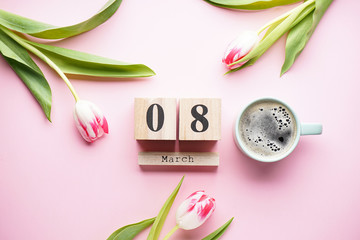 Beautiful tulips with a wooden calendar and a cup of coffee on a pink background. 8 March, International Women's Day.