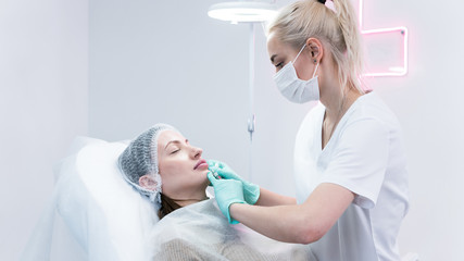 The young beautician doctor preparing to making injection in female lips. The doctor cosmetologist...