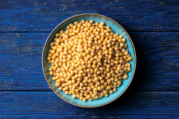 Chickpeas in a bowl on a dark blue wooden background