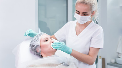 The young beautician doctor preparing to making injection in female lips. The doctor cosmetologist makes lip augmentation procedure.