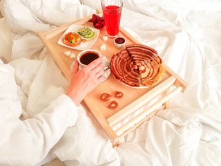 Morning awakening. A leisurely homemade breakfast in a white bed for a girl.