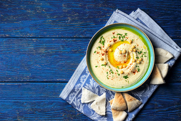 Chickpea hummus in a bowl on a dark blue wooden background
