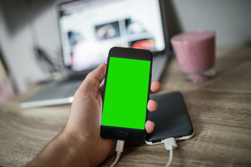 Man holding mobile phone in his hand that is charging with power bank