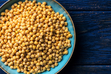 Chickpeas in a bowl on a dark blue wooden background