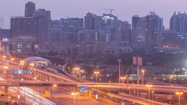 Dubai Golf Course with a cityscape of Gereens and tecom districts at the background aerial night to day transition timelapse. Traffic on sheikh zayed road with junction