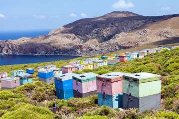 Colorful wooden beehive boxes on the Mediterranean sea cliff with rocky mountain in the background .