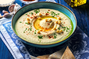 Chickpea hummus and various ingredients on a dark blue wooden background