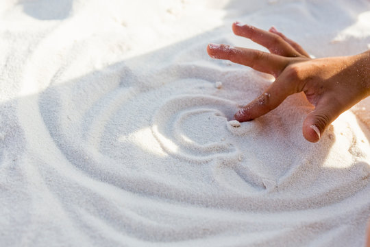young boys hand making a design in sand,White Sands National Monument
