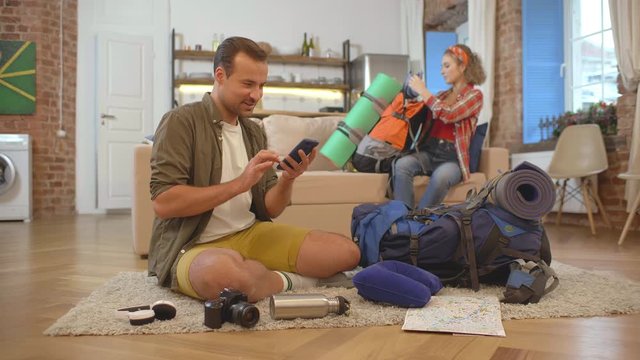 Couple of tourists preparing for hiking tour together.