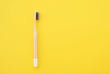 Stylish eco friendly natural bamboo toothbrush on yellow background.
