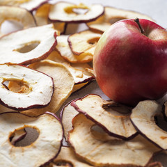 Sliced dried apples ready to eat on a wooden table and fresh apple . Top view
