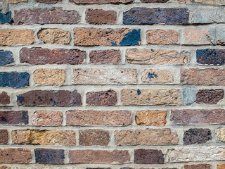 Rectangular brick wall of different colours in grey cement